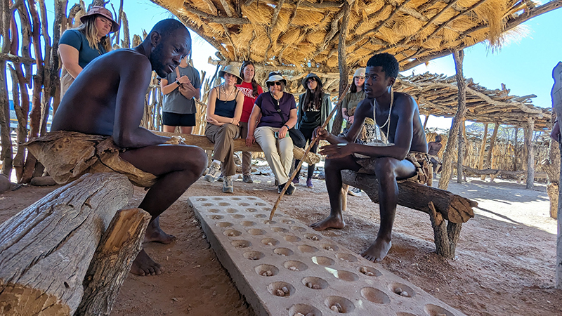 Damara men show students how to play board game