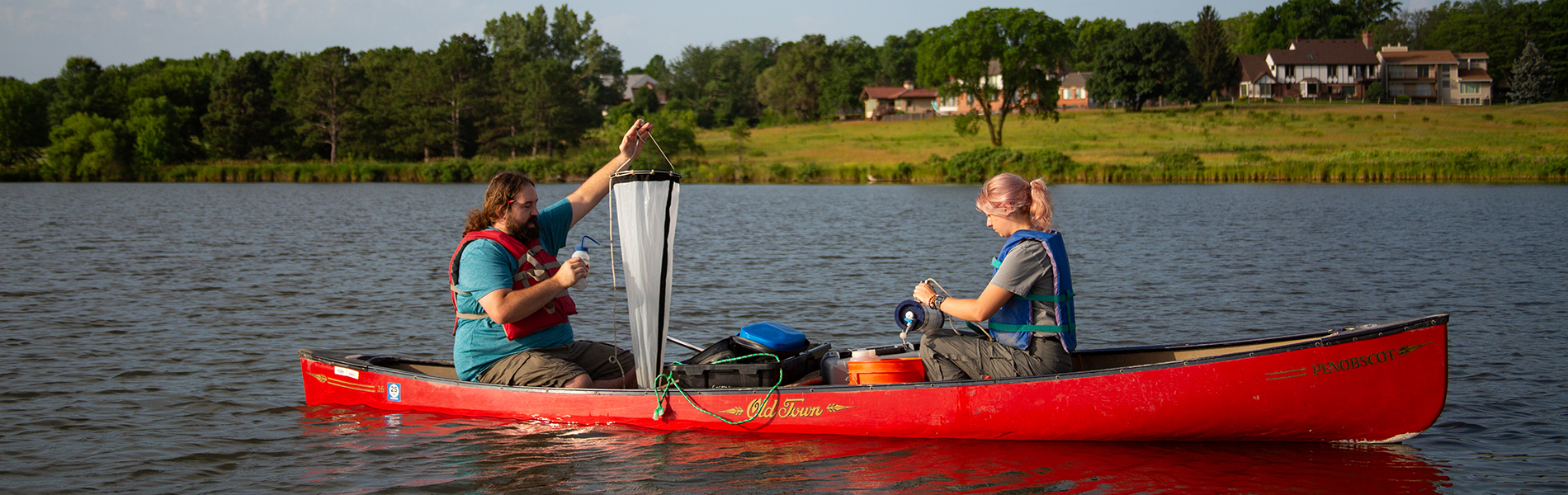 Two students in canoe holding net up